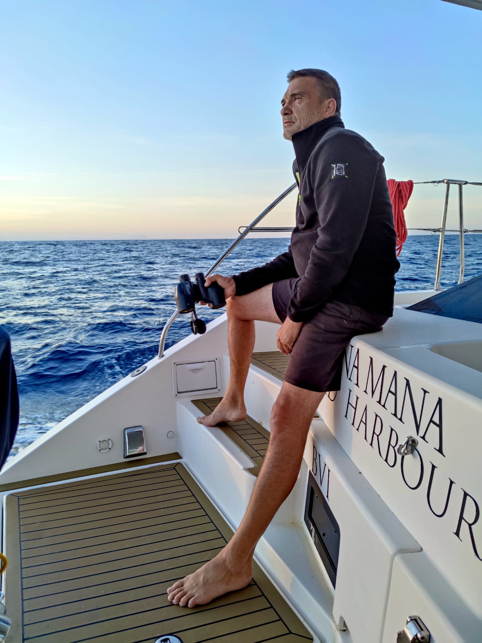 шкипер сидит на корме катамарана